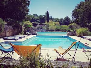 una piscina con due sedie e una piscina di La Loge du Grand Cèdre, chambre d'hôtes SoCosy a Fontcouverte