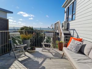 a patio with two chairs and a couch on a house at Pura Vida by the Sea in Riverton