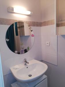 bagno con lavandino e specchio di Meublés de tourisme LE TRIANON et LE PETIT TRIANON a Saint-Junien