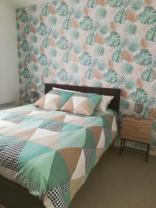 una camera con un letto con una trapunta colorata di Meublés de tourisme LE TRIANON et LE PETIT TRIANON a Saint-Junien