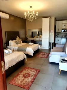 duża sypialnia z 2 łóżkami i żyrandolem w obiekcie Suikerbossie Guesthouse w mieście Bloemfontein
