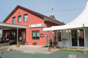um edifício vermelho com uma tenda branca em frente em Gasthof Sonnenterrasse - 24h Self-Check-in em Litzelsdorf