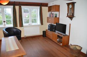 a living room with a tv and a dining table at Altenteil in Oldsum