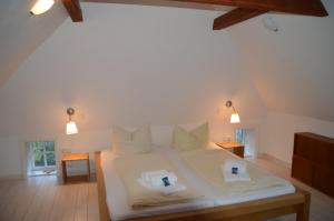 a bedroom with a white bed with two candles on it at Altenteil in Oldsum