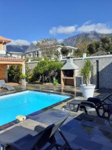 a swimming pool with lounge chairs and a house at La perle des montagnes in Cilaos