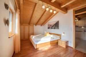 een slaapkamer met een bed en een houten plafond bij Tonigbauernhof Enzian in Schenna