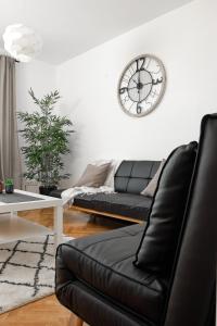 a black couch in a living room with a clock on the wall at Apartamento El Coso in Logroño