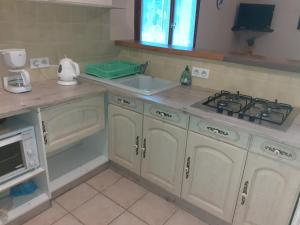 una cucina con armadi bianchi, lavandino e piano cottura di les lavandes a Montjay
