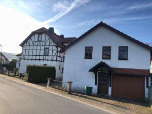 uma casa branca com uma garagem castanha numa rua em Ferienwohnung Familie Tröger em Floh