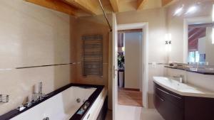 a bathroom with a tub and a sink at Chesa Seraina Abitaziun Seraina 9 - Mahogany - Madulain in Madulain +17 photos