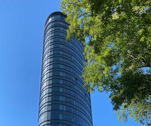 un alto edificio di vetro con un albero di fronte di Thon Partner Stavanger Forum Hotel a Stavanger