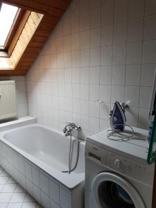 uma casa de banho com uma máquina de lavar roupa e uma banheira em Entspannungsurlaub mit Hund em Aufʼm Bühl