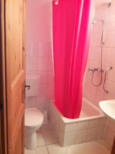 baño con cortina de ducha rosa y aseo en Landhaus-Marwede App 4 en Haffkrug