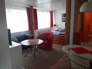 ein Wohnzimmer mit einem roten Stuhl und einem Tisch in der Unterkunft Landhaus-Marwede App 4 in Haffkrug