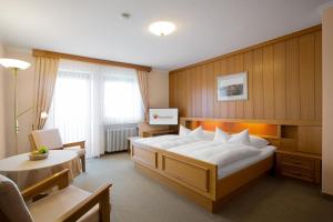 ein Hotelzimmer mit einem großen Bett und einem Stuhl in der Unterkunft Gästehaus Prinzregent Luitpold in Bad Steben