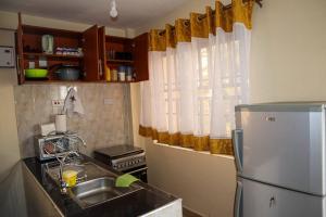 a kitchen with a sink and a refrigerator at Tom Mboya Estate - Fast WI-FI, Netflix and Parking 1Br Apartment in Kisumu Town in Kisumu
