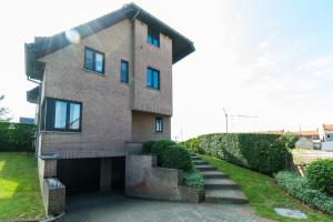 a brick house with a garage and stairs in front at Studio De Groene Golf in Middelkerke