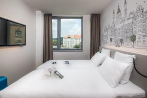 ブダペストにあるB&B Hotel Budapest Cityの白いベッドと窓が備わるホテルルームです。