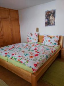 ein Bett mit einer Blumendecke und Kissen darauf in der Unterkunft Appartment am Egghof in Oberperfuss