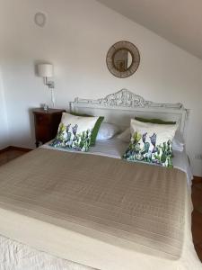 a white bed with pillows and a mirror on the wall at Tyrrhenian Sea Apartment in Torre Faro