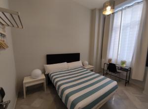 1 dormitorio con 1 cama con manta a rayas en New Samay Hostel, en Sevilla