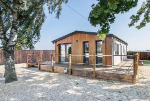 Cabaña de madera pequeña con valla y árbol en Hideaway by Liv Retreats en Lincoln