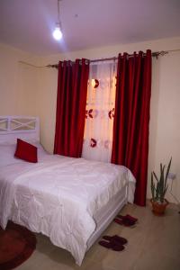 a bedroom with red curtains and a bed with shoes on the floor at Tom Mboya Estate - Fast WI-FI, Netflix and Parking 1Br Apartment in Kisumu Town in Kisumu