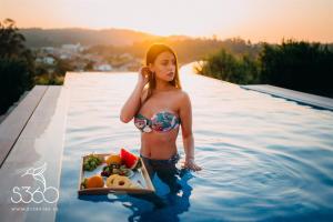 una mujer en una piscina con una bandeja de fruta en Casa Albarari Boutique Double Rooms with access to shared Infinity Pool en Sanxenxo