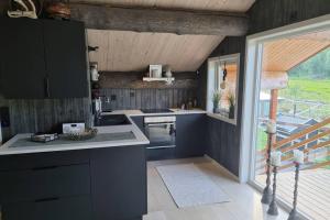 uma cozinha com armários pretos e uma grande janela em Garasjeleilighet med kort vei til flott natur, Måndalen, Rauma em Sæbø
