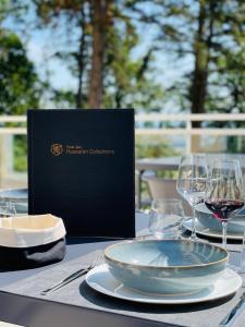 a table with a plate of food and wine glasses at Hotel SPA Husseren Collections - Proche Colmar - Eguisheim in Eguisheim