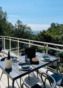 una mesa con platos y copas de vino en el balcón en Hotel SPA Husseren Collections - Proche Colmar - Eguisheim en Eguisheim