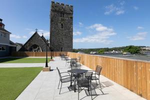 a patio with tables and chairs and a wooden fence at Pembroke Self Catering Apartments in Pembroke