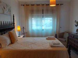 a bedroom with a large bed with a chair and a window at Casa Luz in Vila Nova de Milfontes
