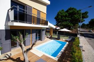 a villa with a swimming pool in front of a house at Beach Villa Lagoa de Albufeira in Lagoa de Albufeira