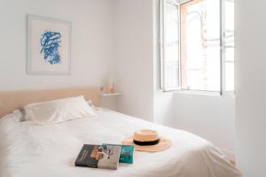 un cappello e un libro su un letto con una finestra di Casa dos Infantes a Muros