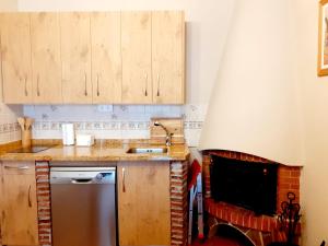 una cucina con piano cottura, lavandino e camino di Adosado Marblés con Txoko y Wifi a Ezcaray