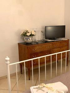 einen Fernseher auf einer Kommode mit einer Blumenvase in der Unterkunft Dream House De Iulio in Pompei