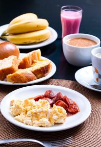 a table with plates of breakfast foods and a drink at Hotel Portal dos Ventos in Parnaíba