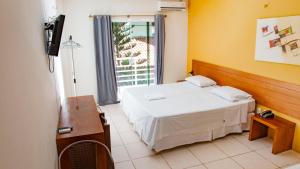 a bedroom with a white bed and a television at Hotel Portal dos Ventos in Parnaíba