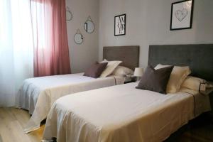 two beds in a hotel room with white sheets at La Casa de Kiko. in Santoña