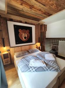 una camera da letto con un letto con un orso appeso al muro di La Tana dell'Orso a Campitello di Fassa