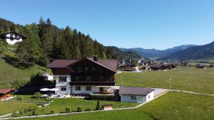 a house in a field with mountains in the background at Frühstückspension Seeblick in Achenkirch