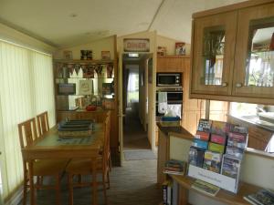a kitchen with a table and a dining room at Cwtch Caravans in Little Haven