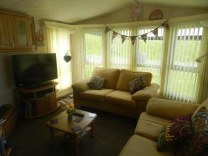 a living room with a couch and a flat screen tv at Cwtch Caravans in Little Haven