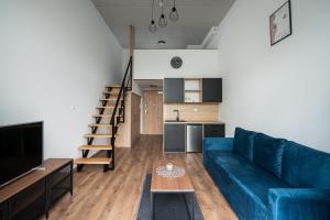 a living room with a blue couch and a kitchen at RentPlanet - Apartamenty Zarembowicza II in Wrocław