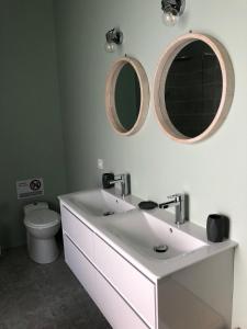 La salle de bains est pourvue d'un lavabo blanc et de deux miroirs. dans l'établissement Maison moderne avec jardin à 750m de la mer, à Pornic