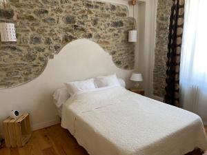 a bedroom with a white bed and a stone wall at Le Logis GOUT in Carcassonne