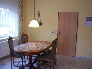 a dining room with a table and chairs and a door at Ferienwohnung Mauer, Wohnung "C" in Heede