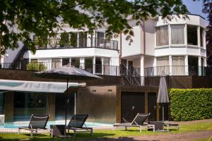 a building with a pool and two chairs and an umbrella at Landgoed Lauswolt in Beetsterzwaag