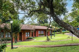 a red building with a tree in front of it at Hotel Estância Barra Bonita in Barra Bonita